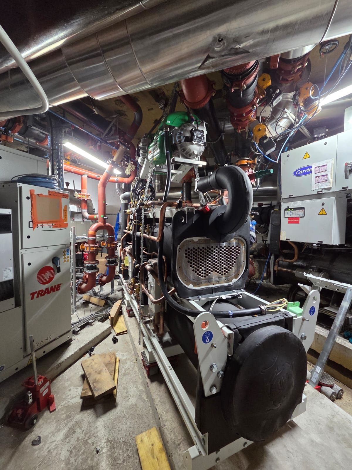 Des machines industrielles dans un local technique exigu, avec des tuyaux et des conduits apparents