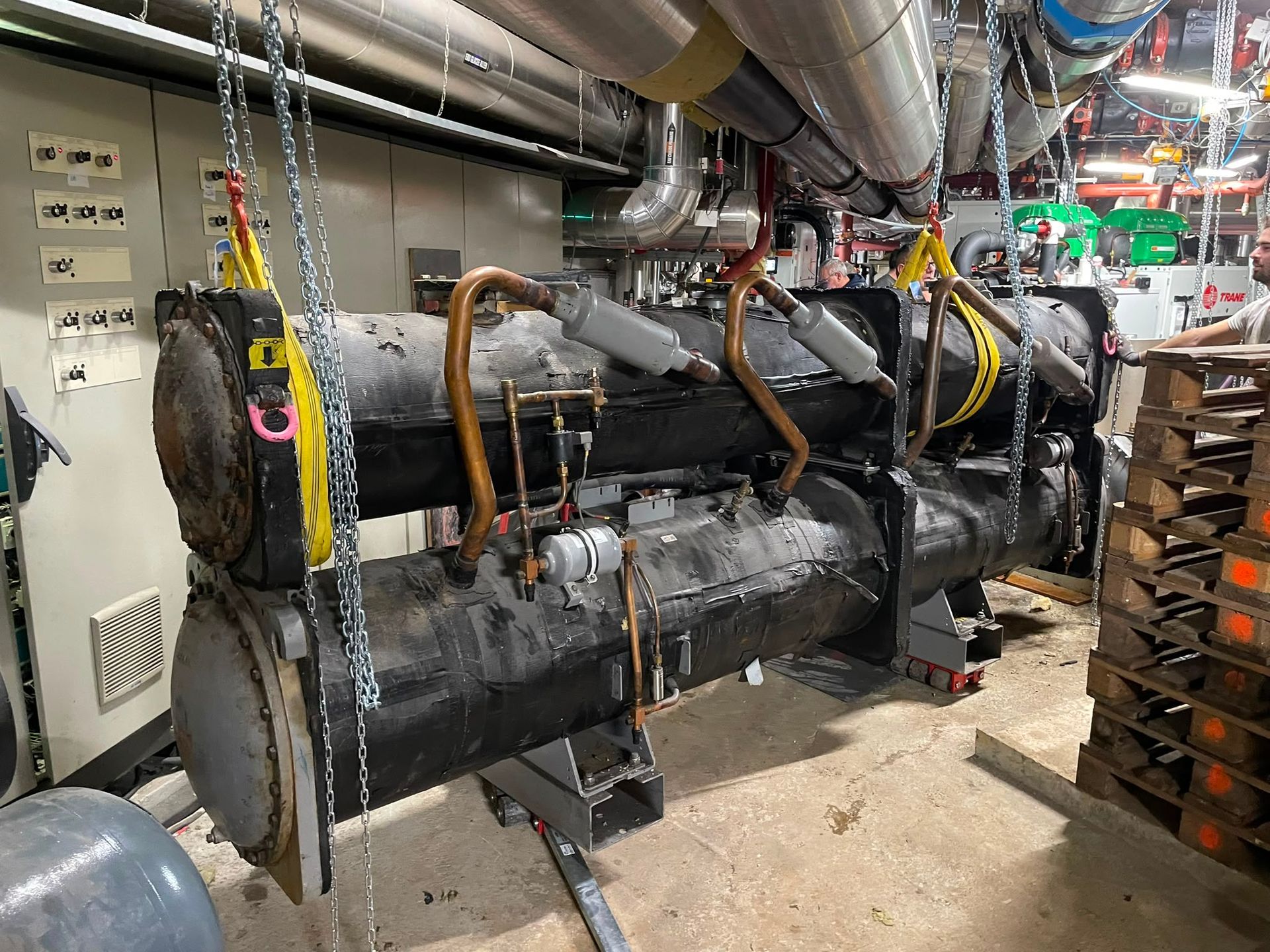 Machinerie industrielle recouverte d’une isolation noire, avec des tuyaux et des câbles dans un atelier d’usine