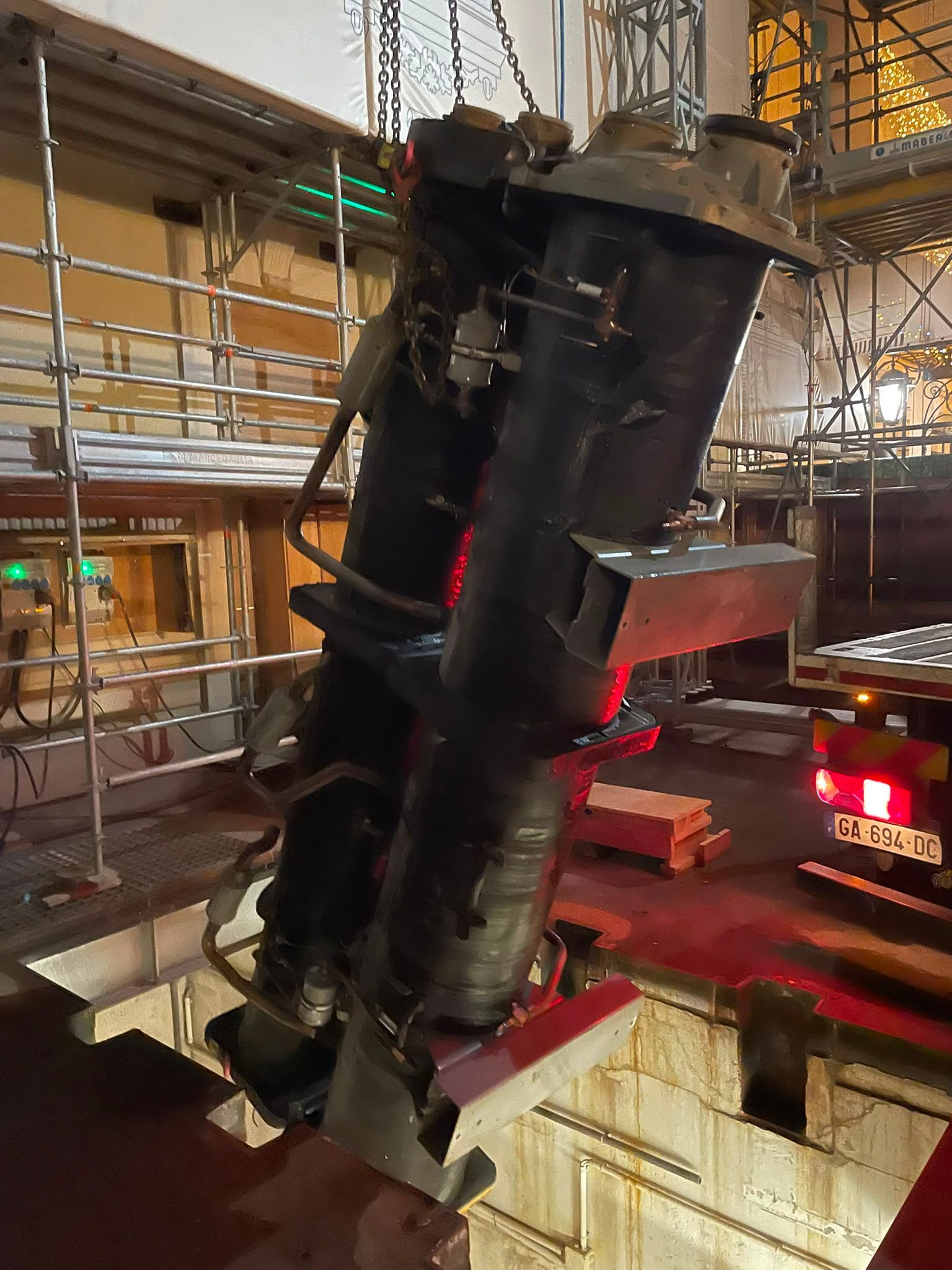 Gros tuyau ou conduit industriel noir suspendu à l’intérieur d’une usine ou d’un entrepôt à plusieurs niveaux
