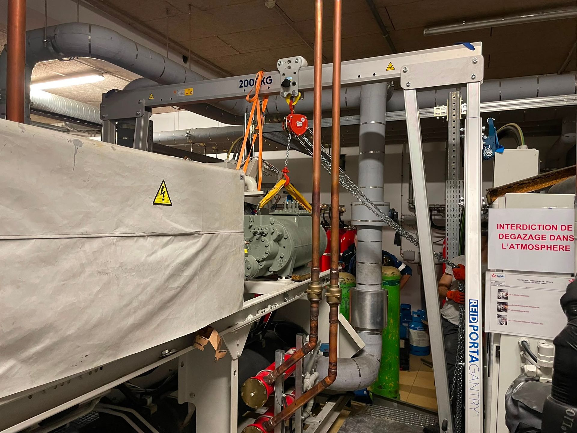 Des machines industrielles avec des tuyaux, des vannes et une partie couverte dans une pièce ressemblant à une usine