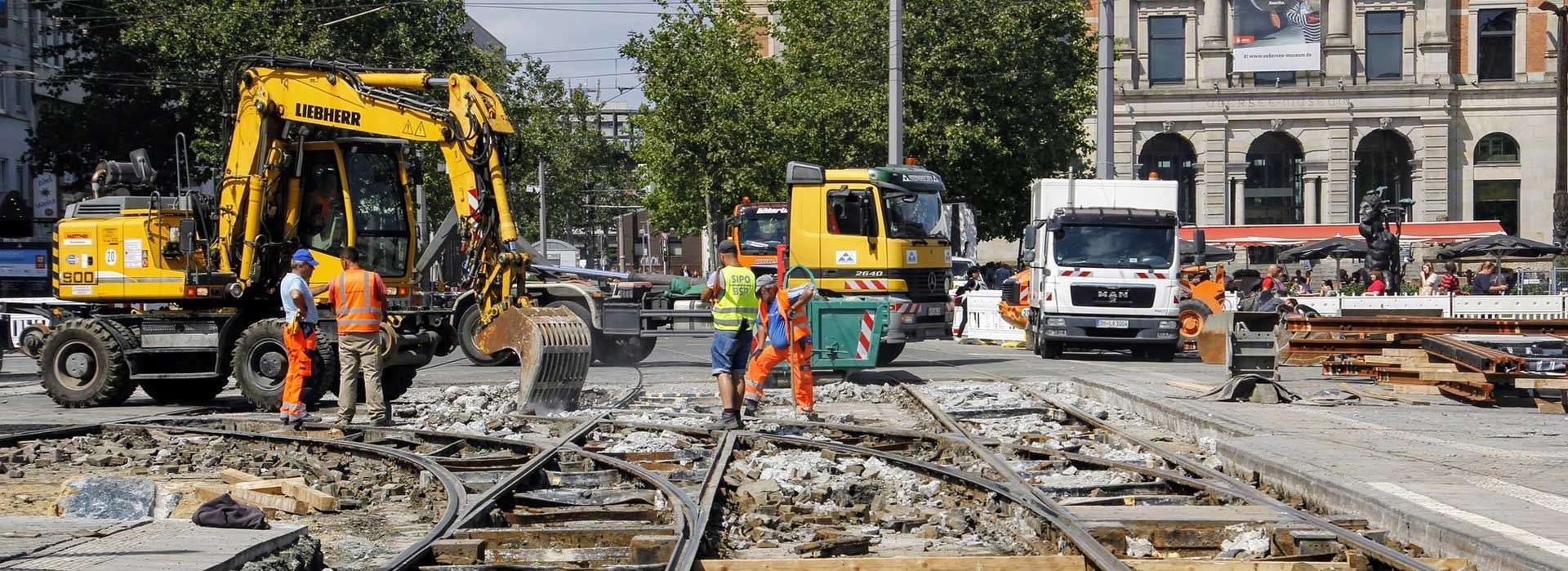 Des ouvriers et des engins de chantier réparent des voies ferrées endommagées dans une rue de la ville.