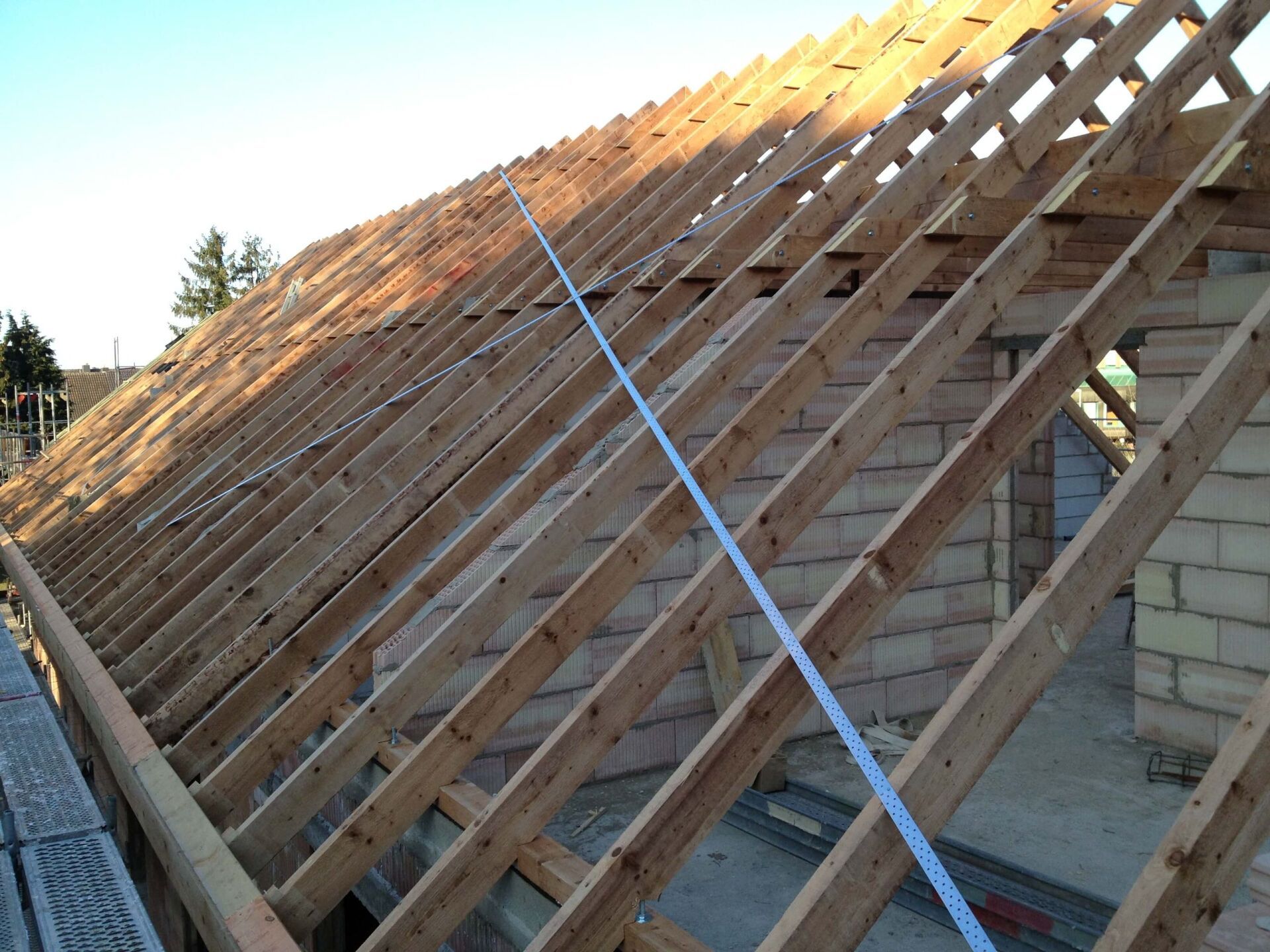 Teilweise im Bau befindliches Dach mit Holzsparren und einem blauen Stützband