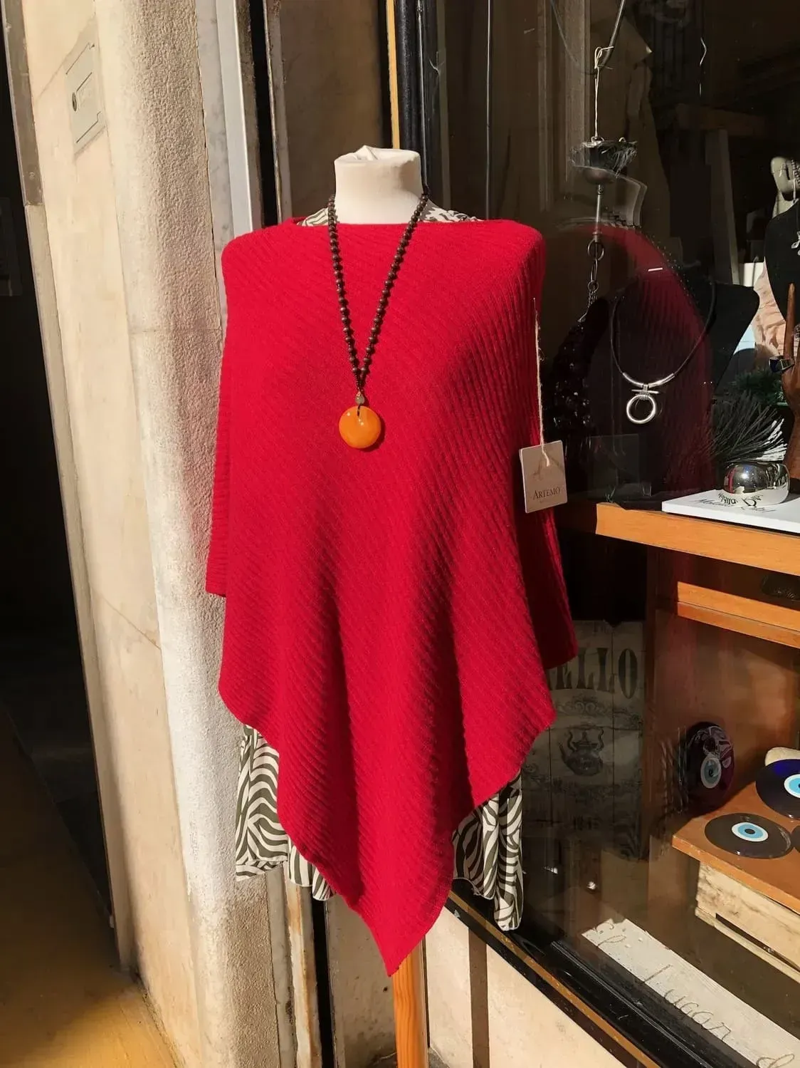 Un poncho rojo con un collar en un maniquí.