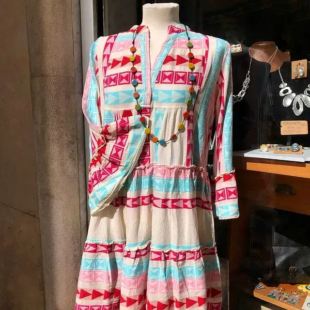 Un maniquí lleva un vestido colorido y un collar.