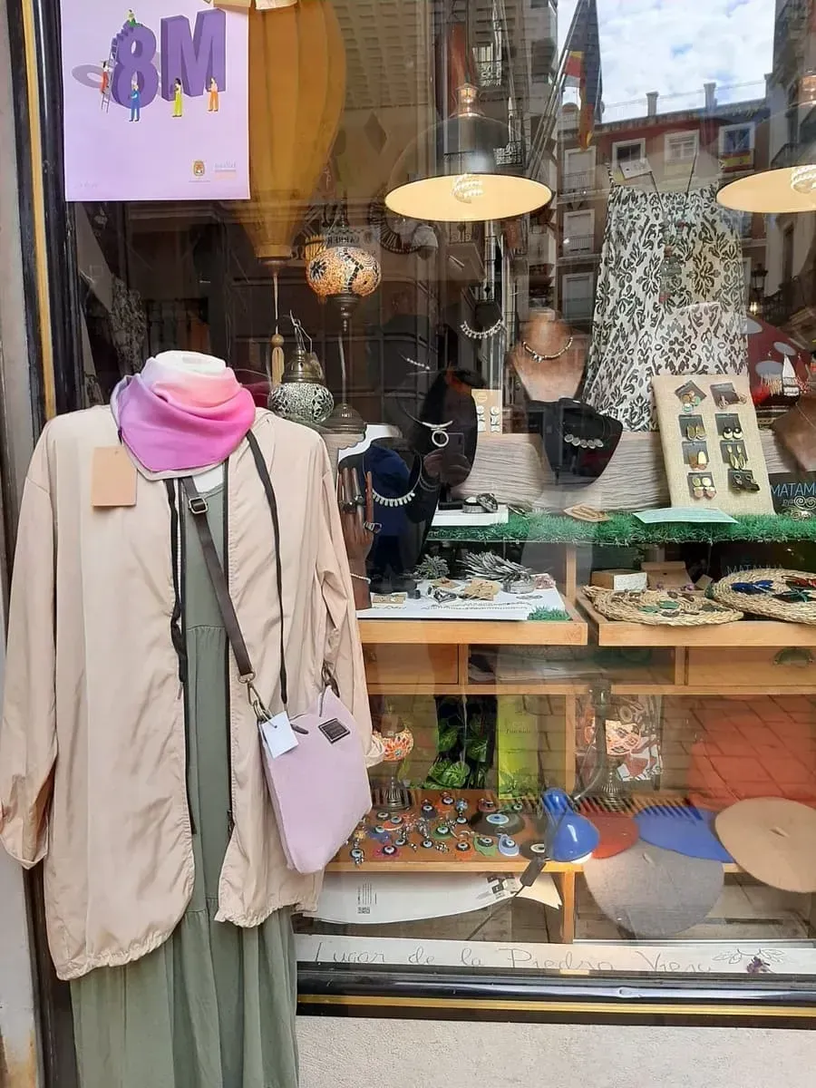 Un maniquí está parado frente al escaparate de una tienda.