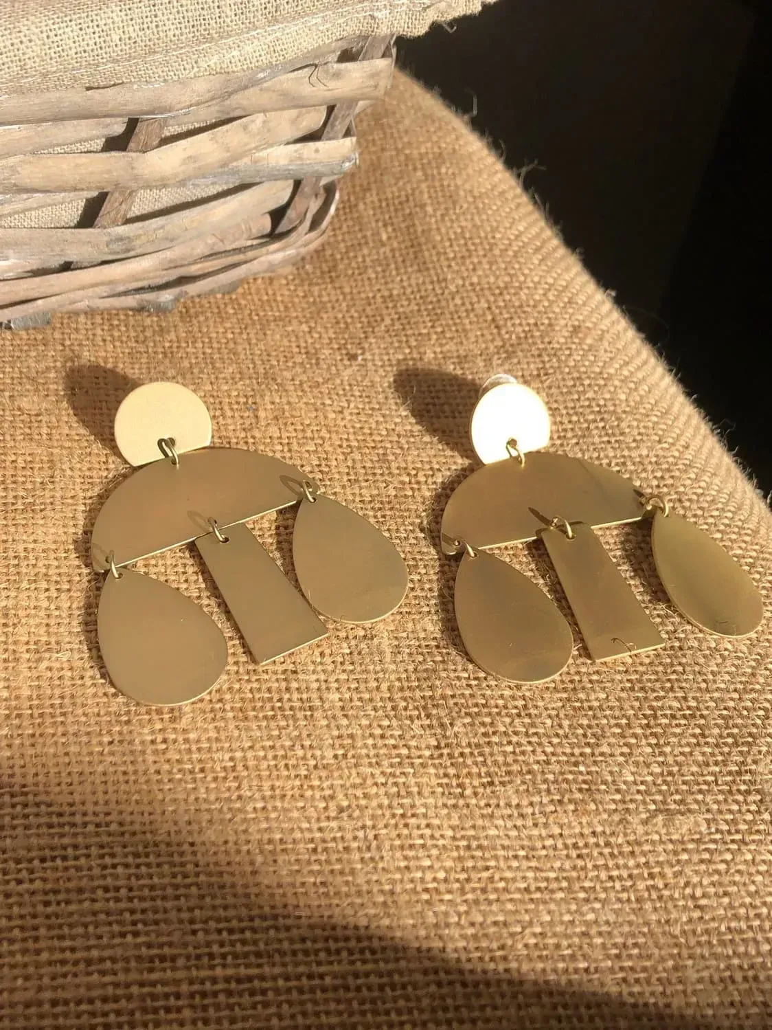 Un par de pendientes de oro están sobre una mesa al lado de una canasta.