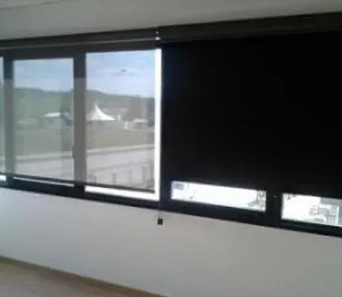 Una habitación con muchas ventanas y persianas negras.