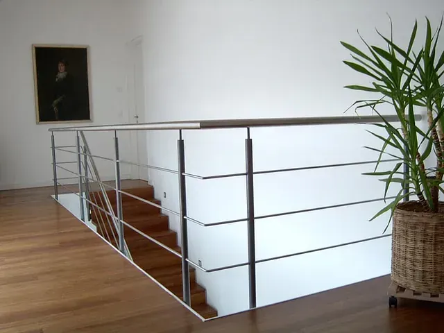 Una escalera con barandilla de acero inoxidable y una planta en maceta.