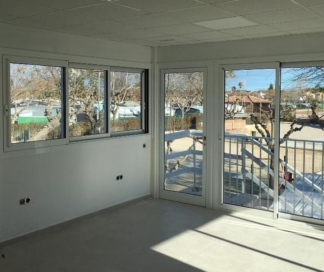 Una habitación con muchas ventanas y puertas corredizas de vidrio.