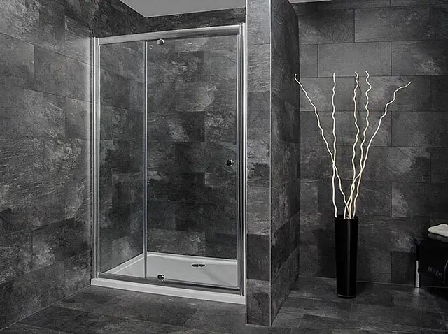 Una fotografía en blanco y negro de un baño con una puerta de ducha corrediza de vidrio.