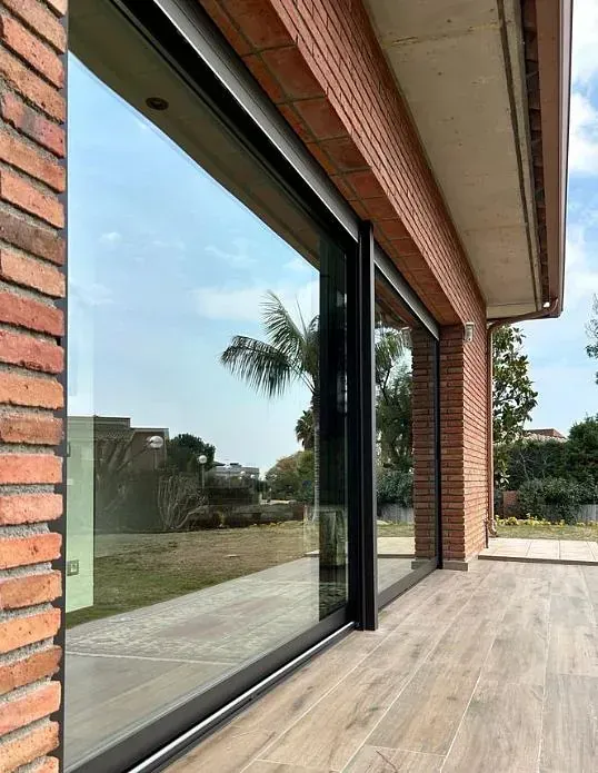 Un edificio de ladrillo con puertas corredizas de vidrio y piso de madera.
