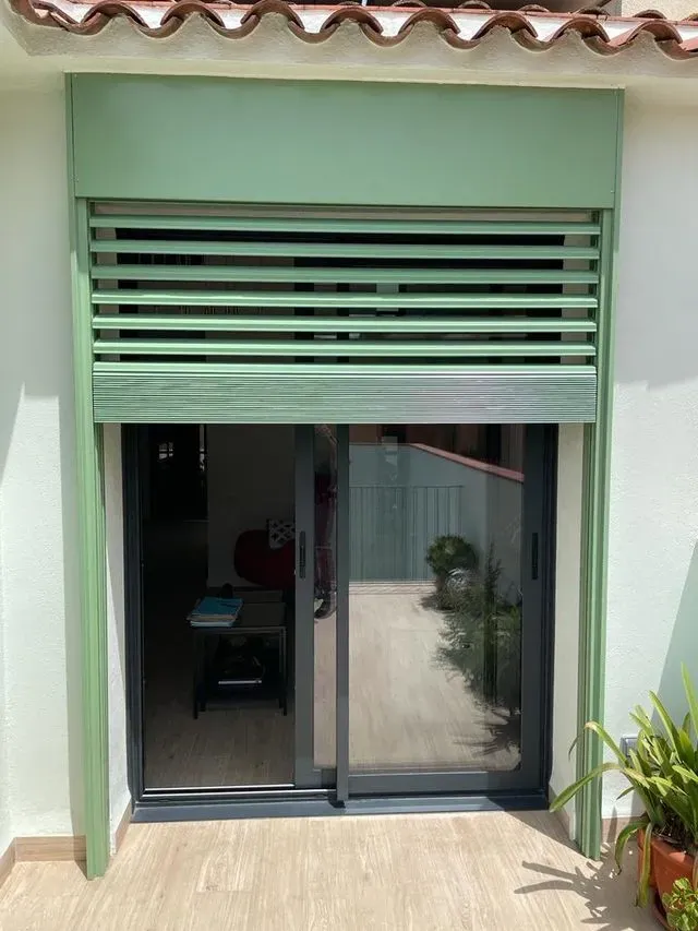 Una puerta corrediza de vidrio con una persiana verde.