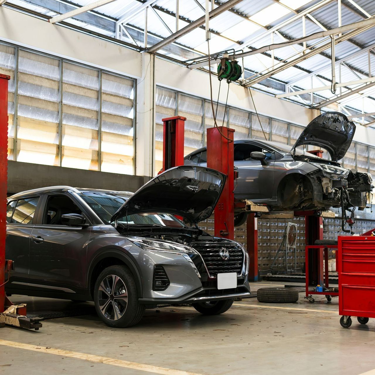 Des voitures grises, avec le capot ouvert, en cours de réparation dans un garage