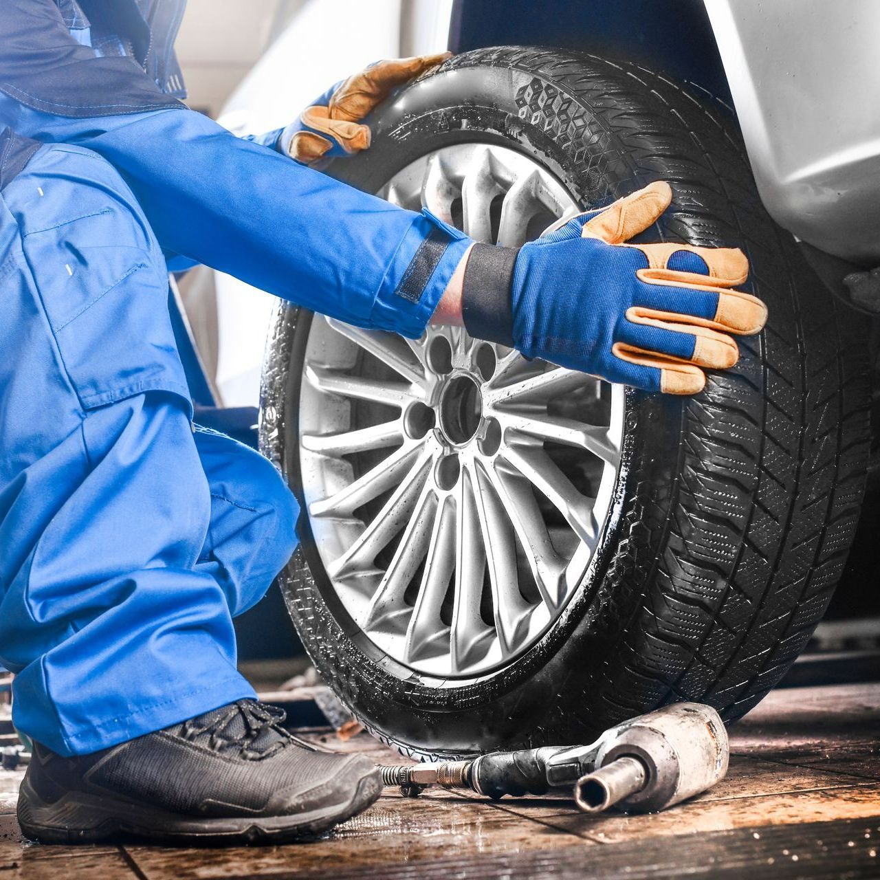 Un garagiste pose ses mains sur le pneu d'une voiture