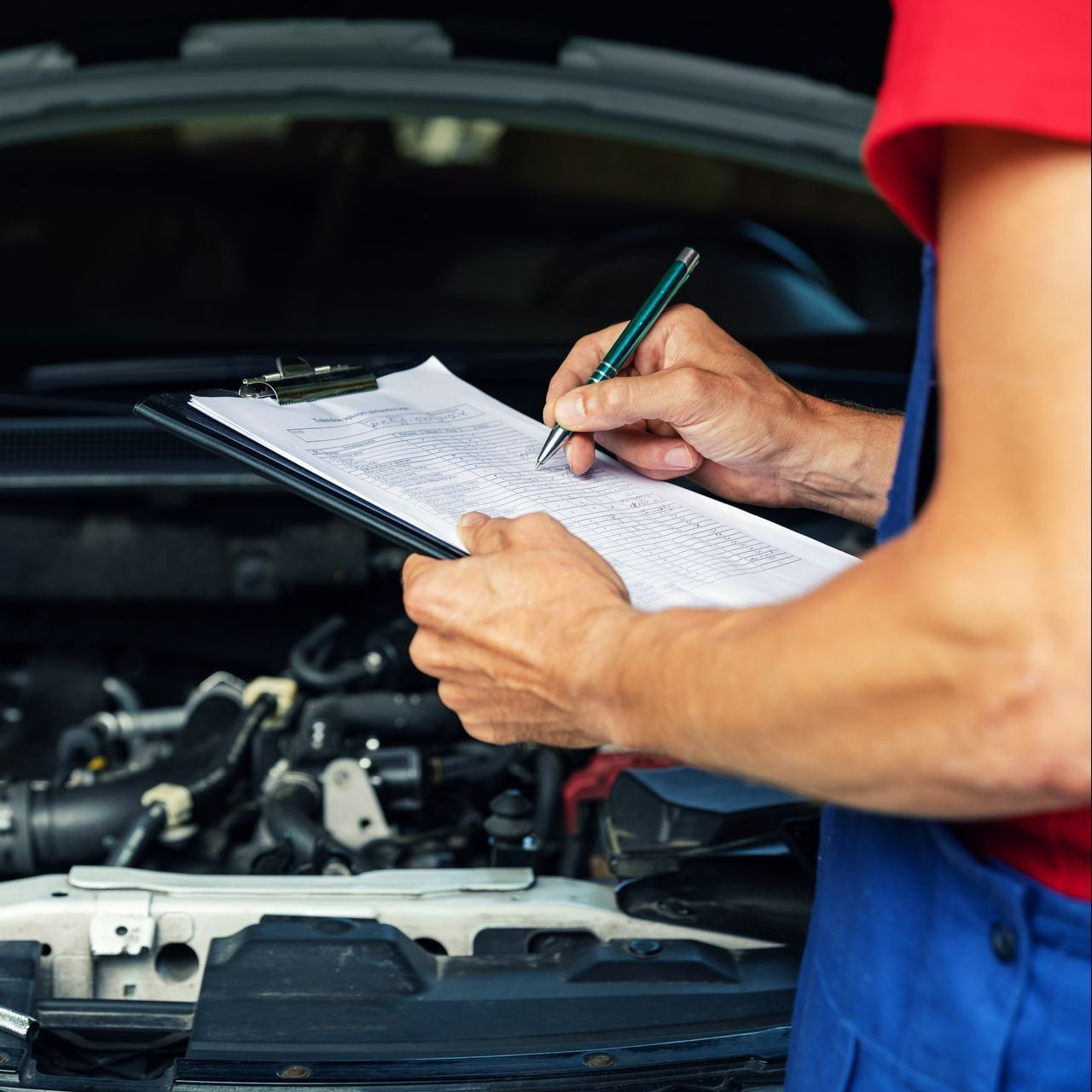 Une homme coche les cases d'une liste en inspectant une voiture