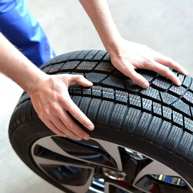 Deux mains posées sur un pneu au sol