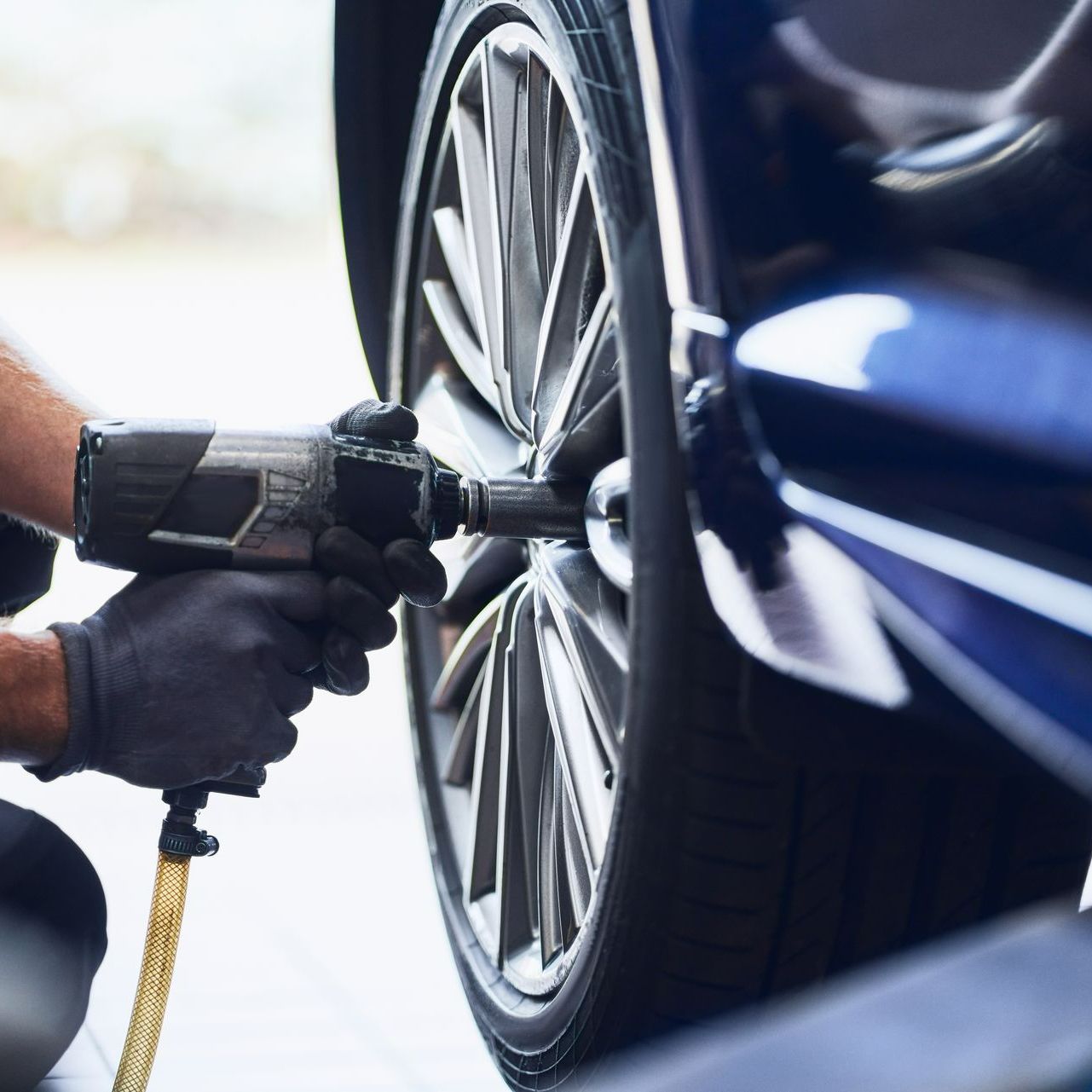 Des mains de garagiste utilisent un outil sur l'un des pneus d'une voiture