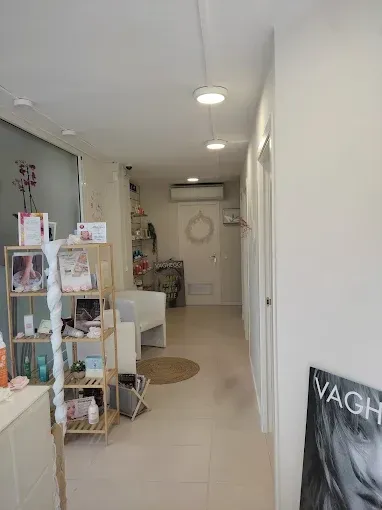 Un largo pasillo en un salón de belleza con estantes y una silla.