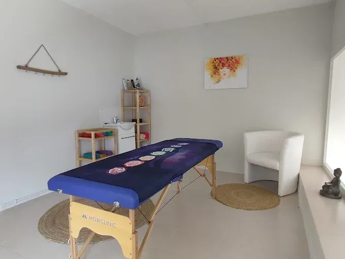 Una mesa de masajes está sentada en una habitación al lado de una silla.