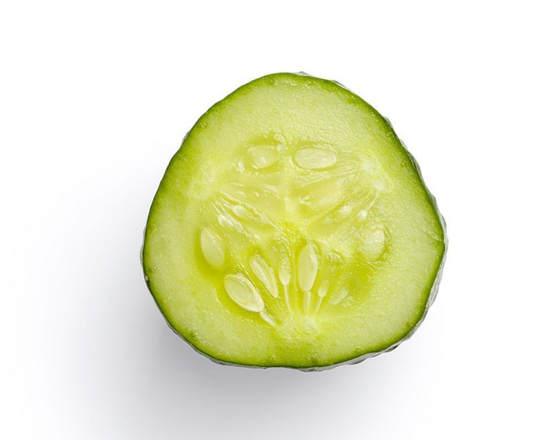 Corte transversal de una rodaja de pepino, que muestra la piel verde y el centro de color claro y lleno de semillas.