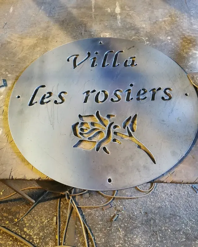 Plaque métallique découpée et une illustration de rose.