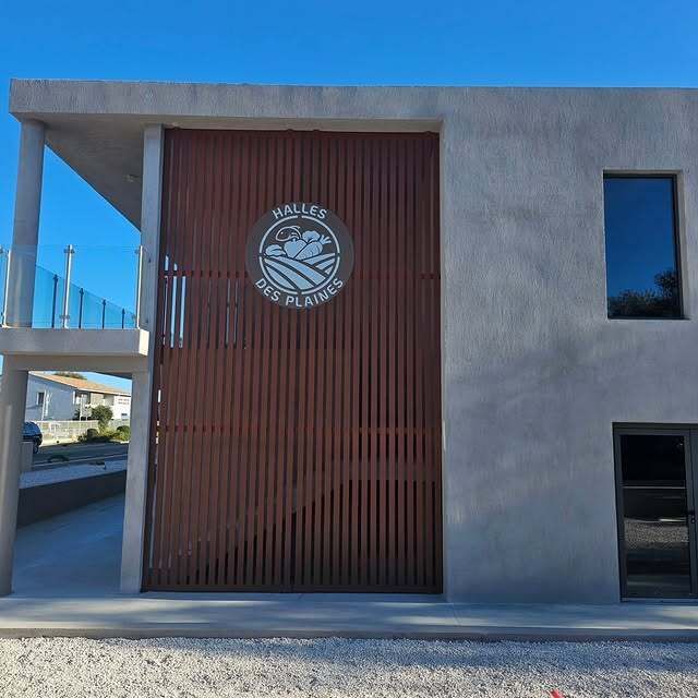 Extérieur d'un bâtiment avec une grande façade en métal et béton.