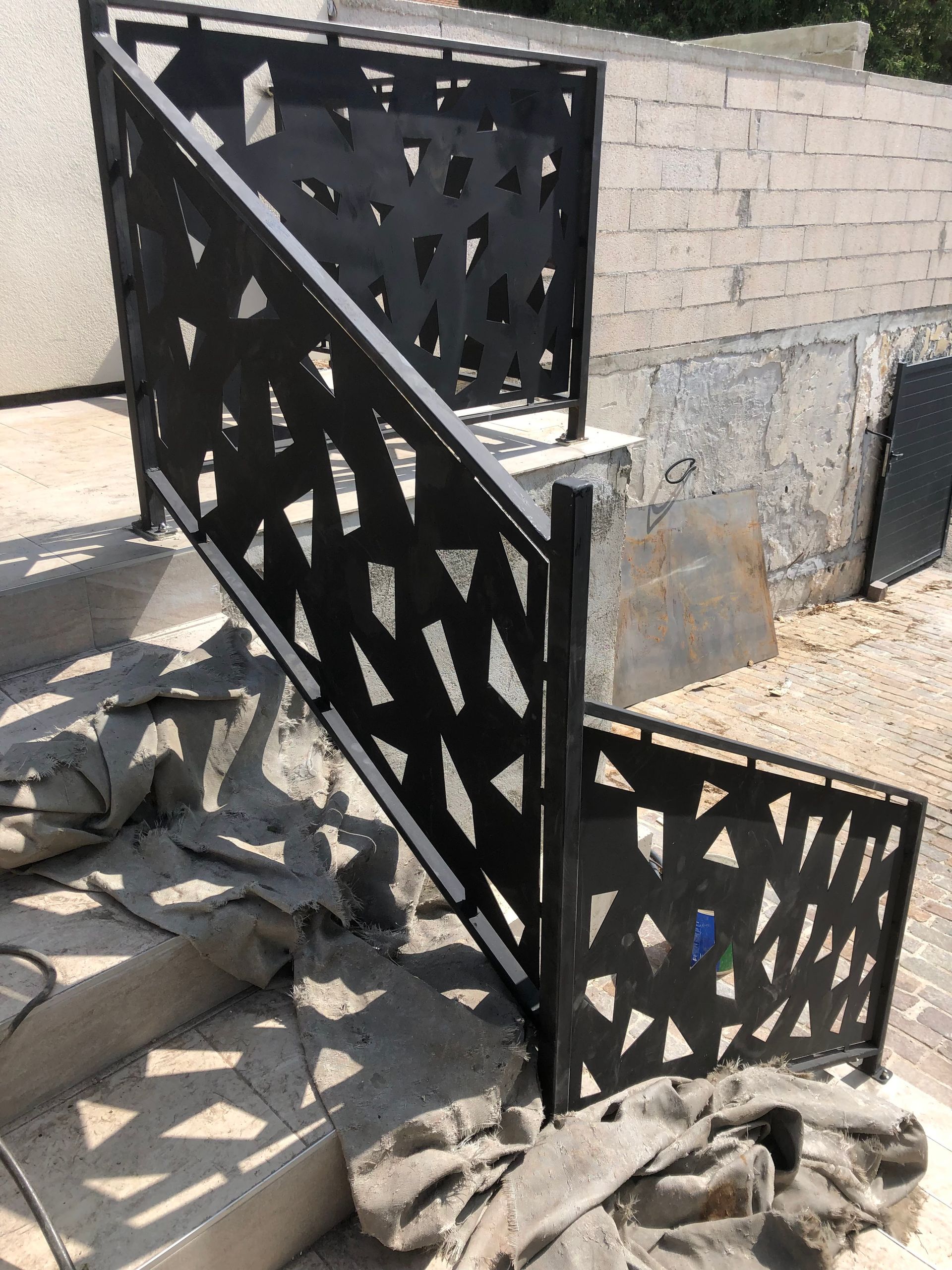 Rambarde d'escalier extérieure en métal noir à motif géométrique.