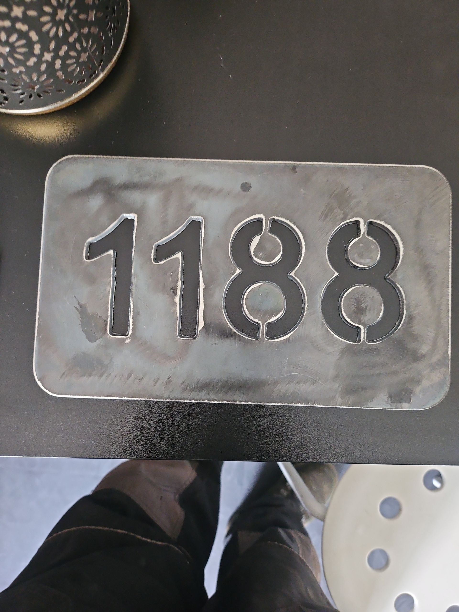Plaque d'adresse en métal avec les chiffres 1188 découpés.