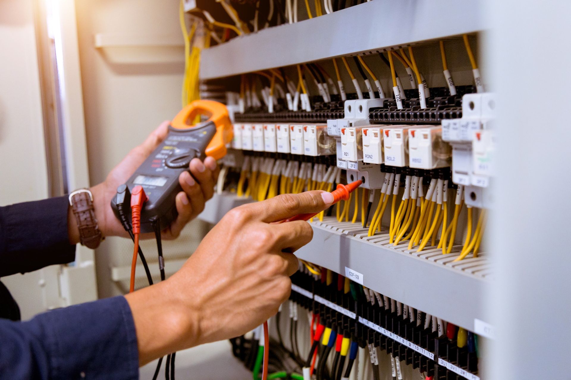 Un electricista está trabajando en un panel eléctrico con un multímetro.