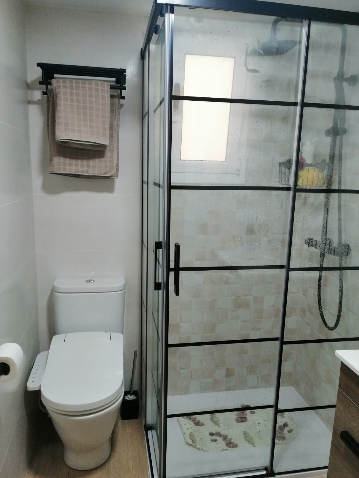 Un baño con inodoro, ducha y ventana.