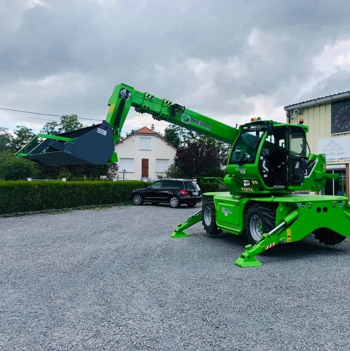 Chariot télescopique vert avec stabilisateurs déployés sur gravier.