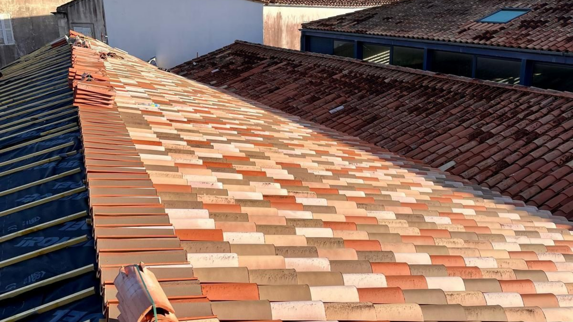 Toits de tuiles aux tons rouge et marron, prise de vue extérieure ensoleillée.