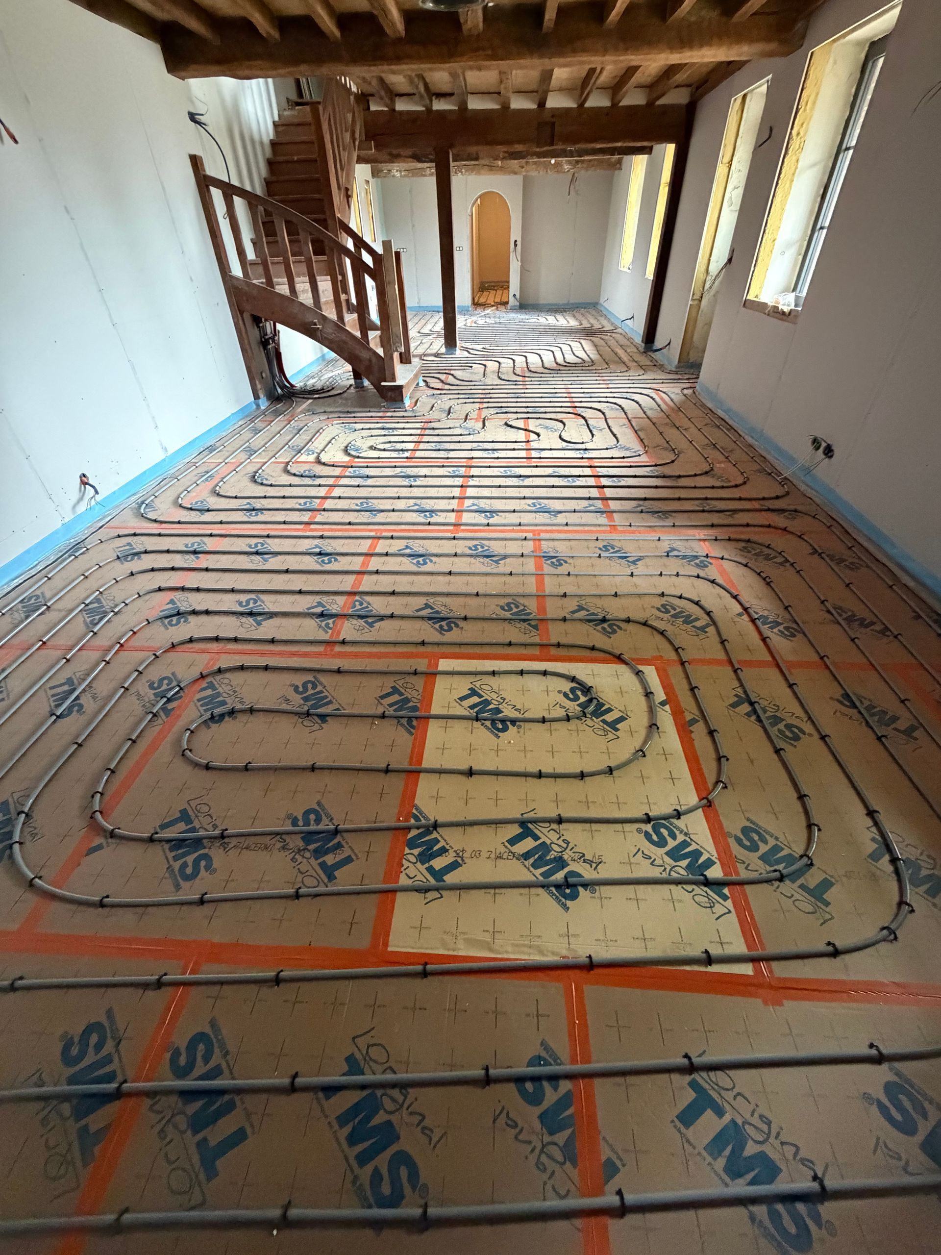 Des pieds nus marchant sur un parquet clair dans une pièce ensoleillée, avec une plante en pot en arrière-plan.