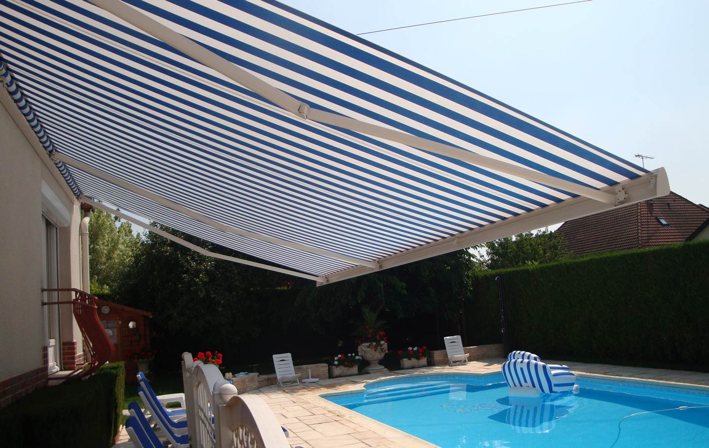 Auvent rayé bleu et blanc au-dessus d'une piscine.