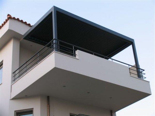 Pergola noire sur un balcon blanc d'un immeuble à étages.