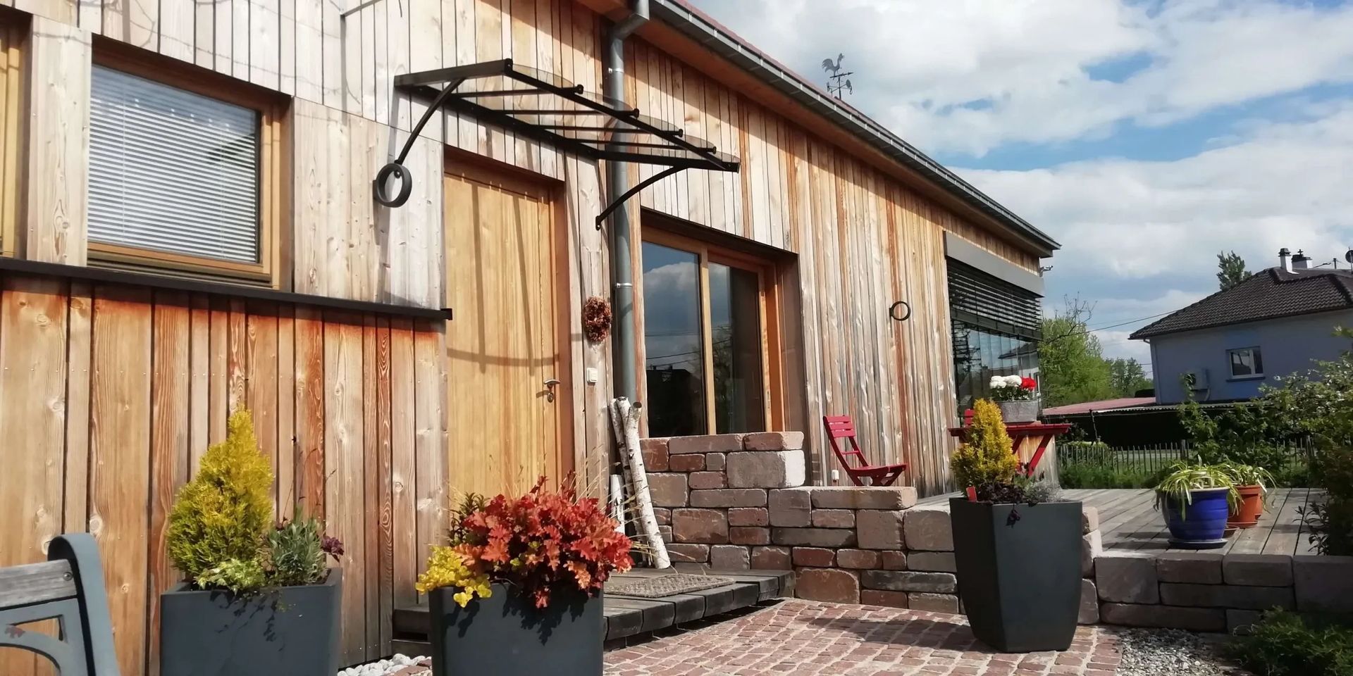 Marquise de marque BVL Serrulac en aluminium sur une façade en bois