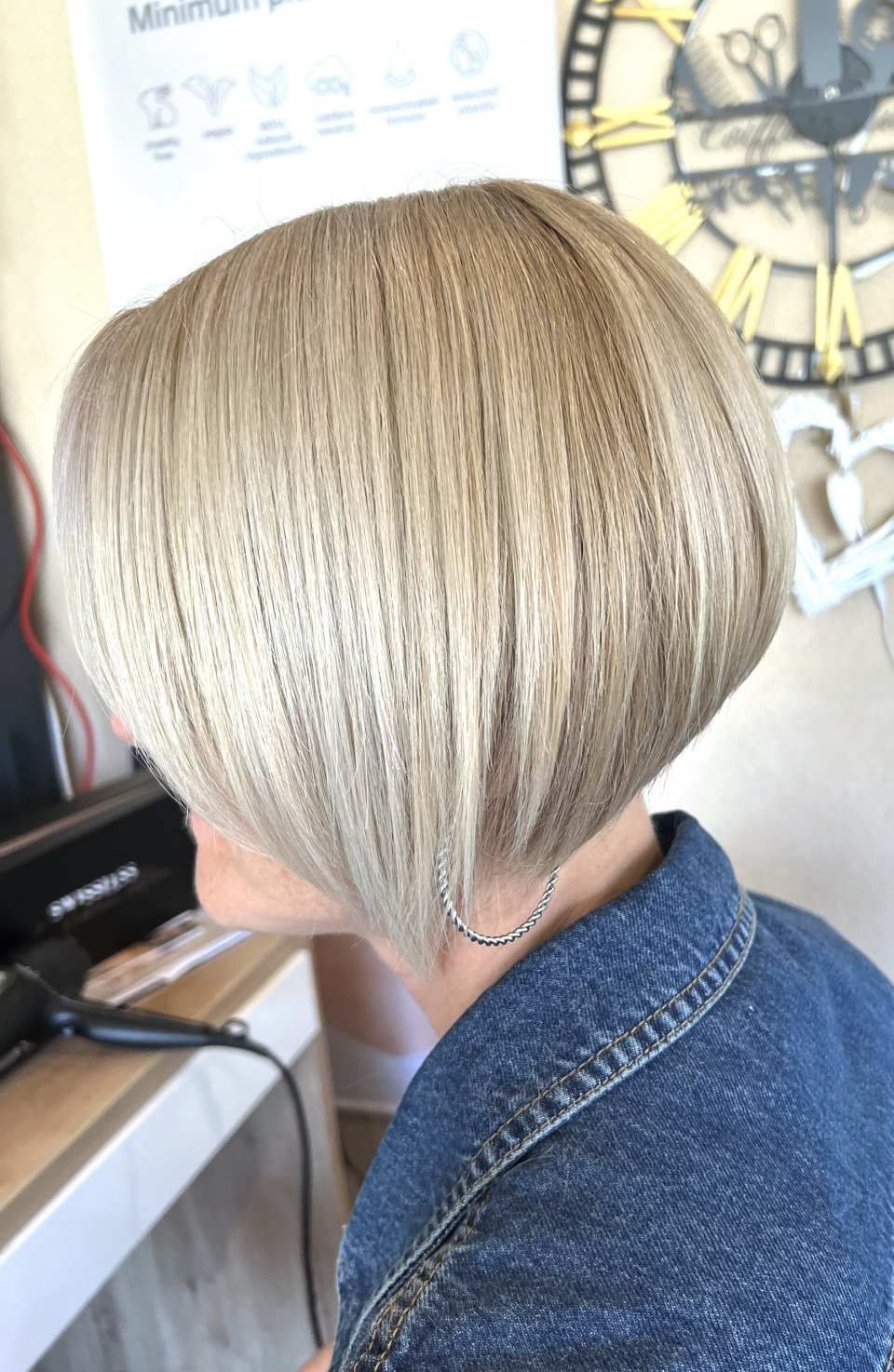 Une femme aux cheveux blonds courts est assise devant une horloge.