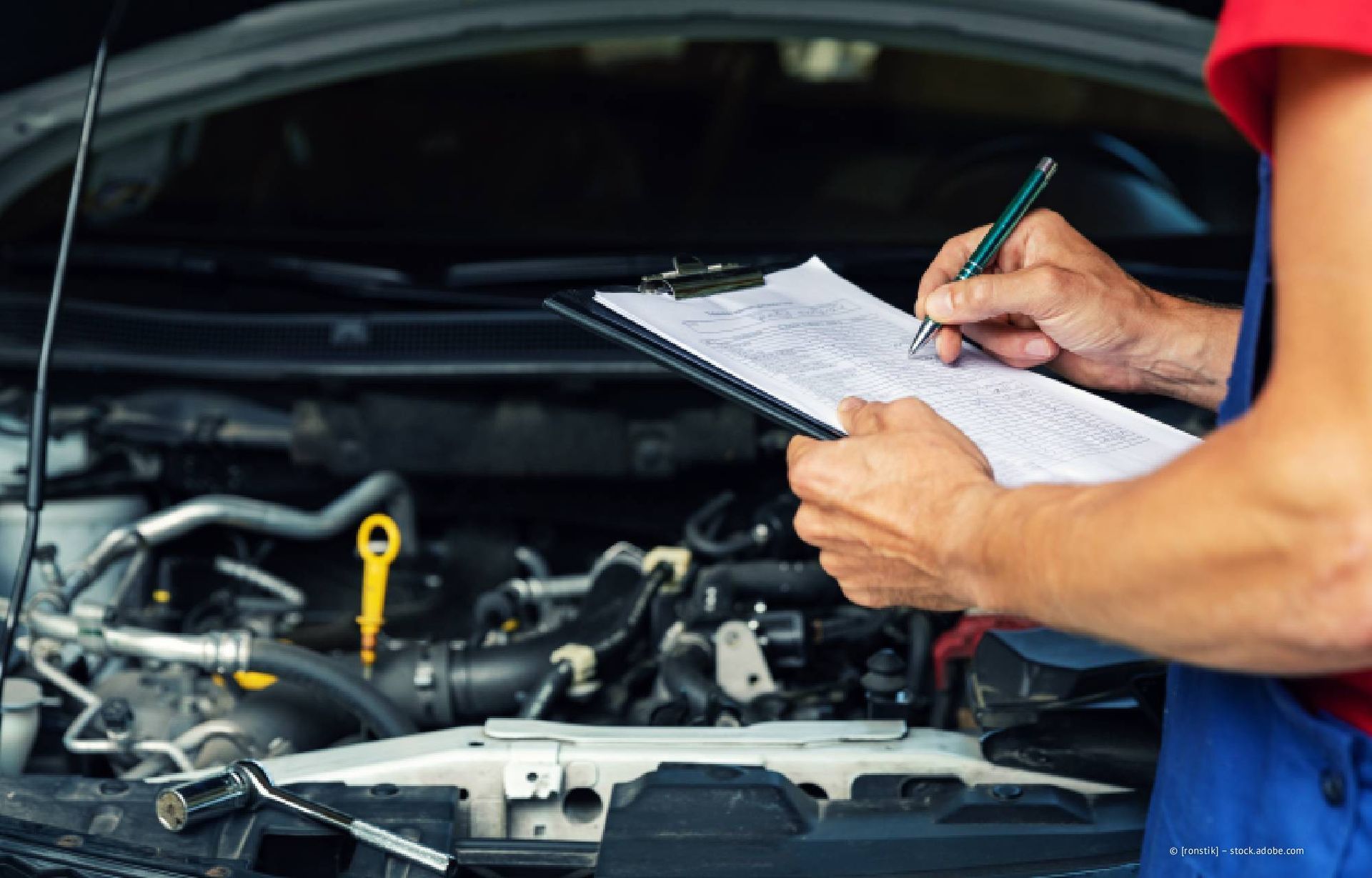 Eine Person poliert in einem Innenraum die Seitenwand eines grauen Autos mit einer Poliermaschine.
