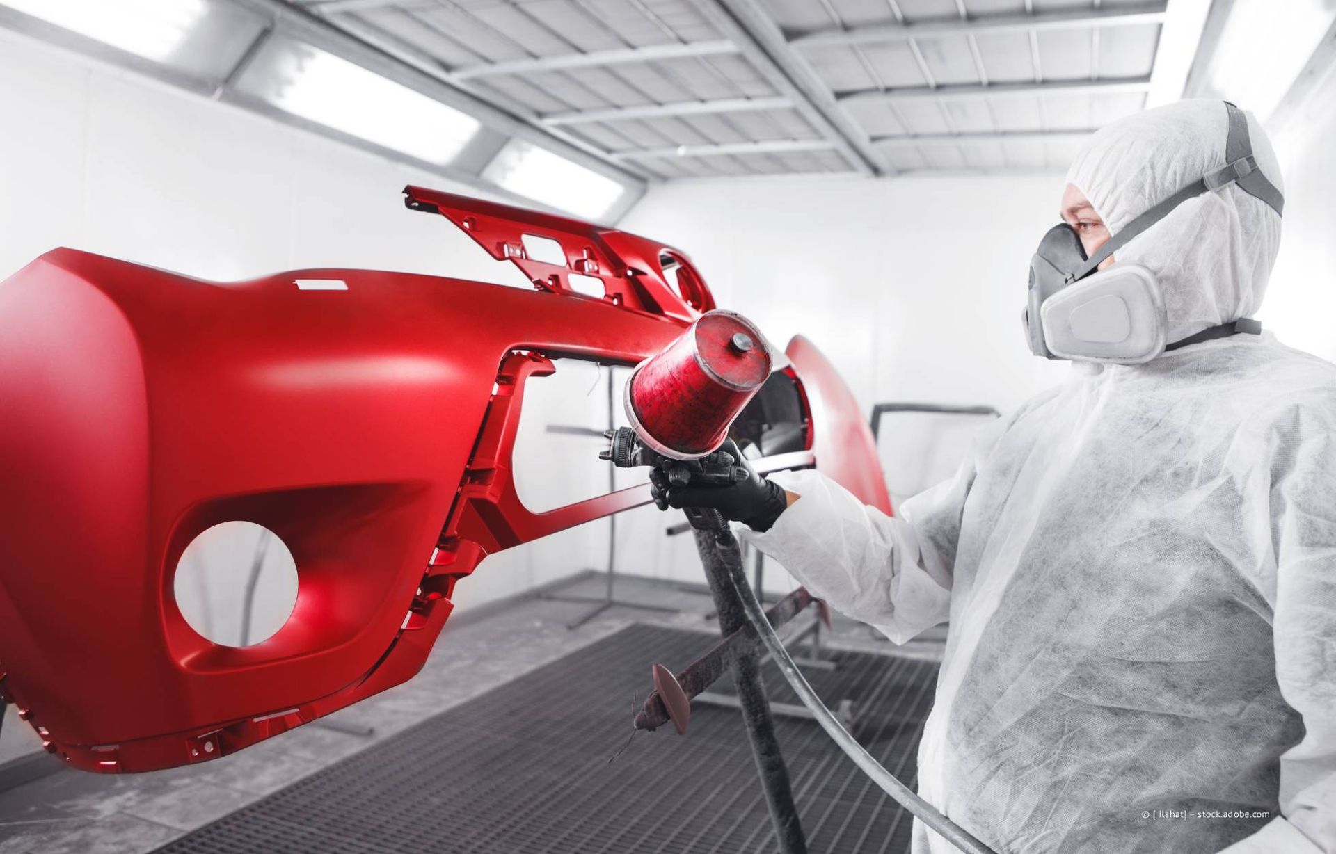 Mann in Schutzkleidung schleift ein Boot in einer Werkstatt.