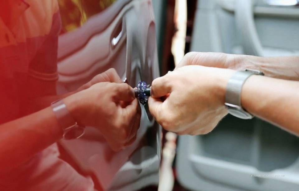 Zwei Männer begutachten den Schaden an der Seite eines weißen Autos, möglicherweise nach einem Zusammenstoß. Einer zeigt auf einen Kratzer.