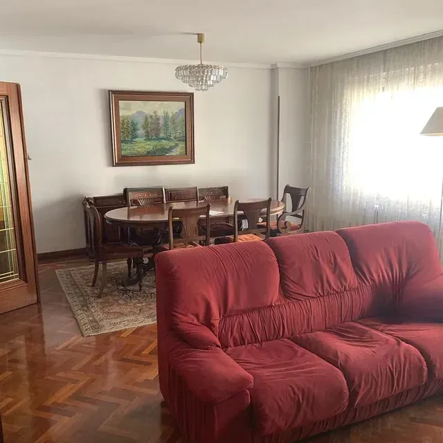 Una sala de estar con un sofá rojo y un cuadro en la pared.