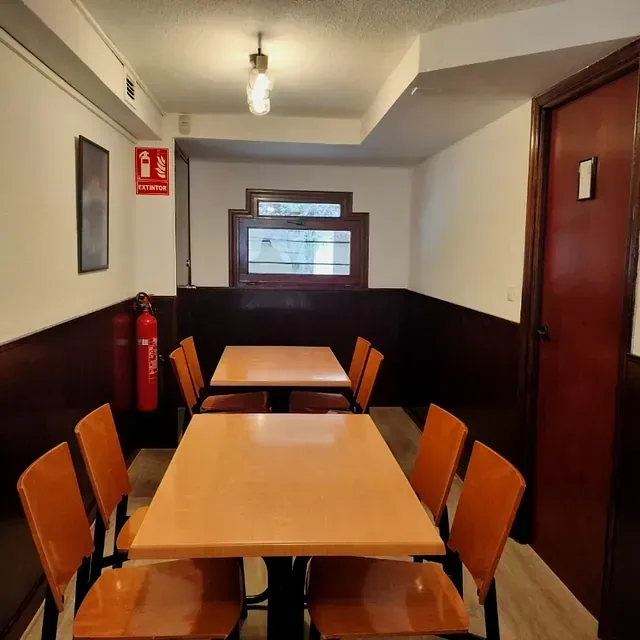 Una habitación con mesas y sillas y un extintor en la pared.