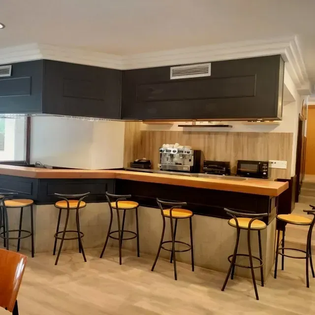 Una cocina con barra y taburetes y una cafetera.