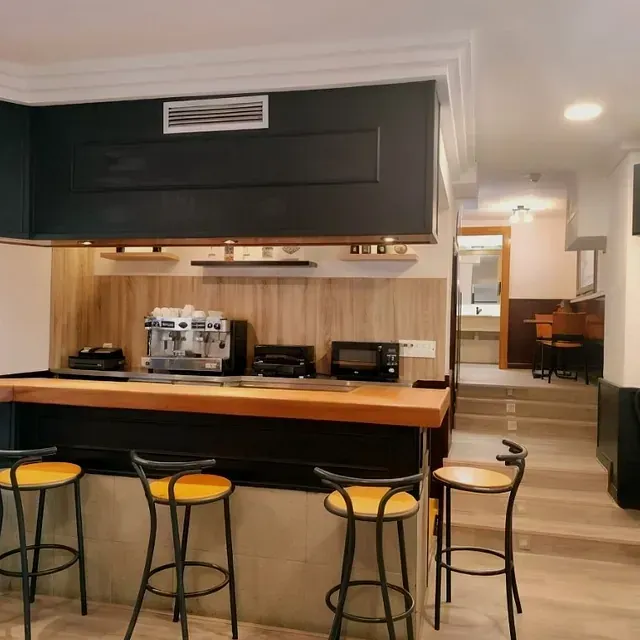 Una cocina con barra y taburetes y una cafetera.