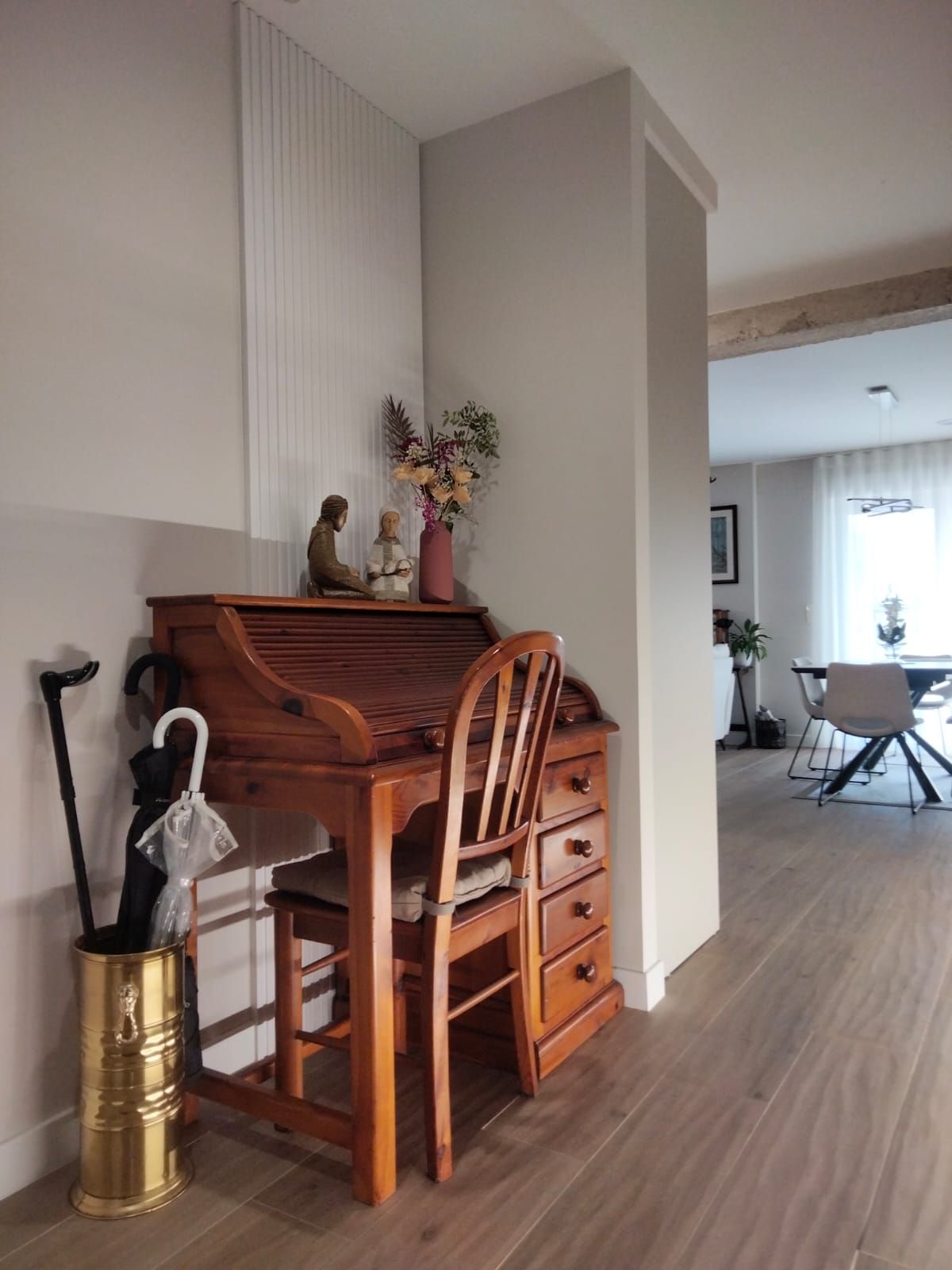 Un escritorio de madera con una silla y un paragüero.