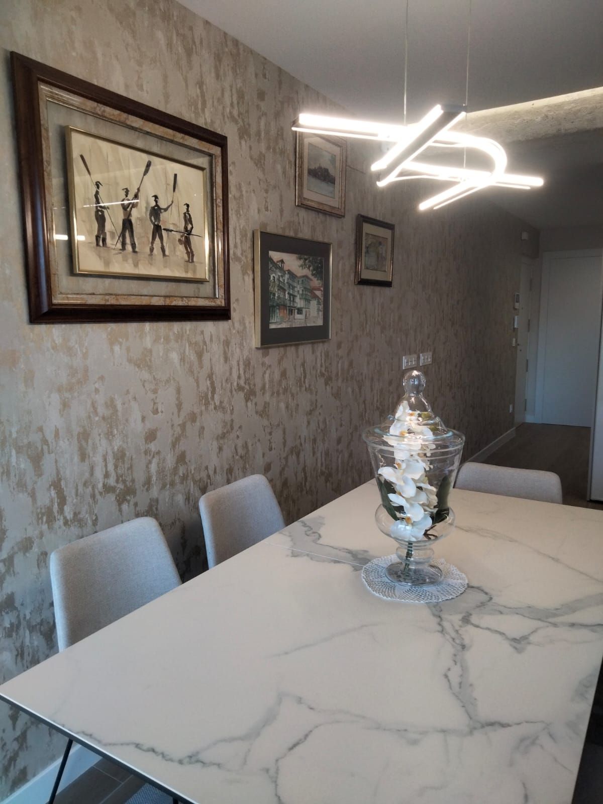 Una mesa de comedor con un jarrón de flores encima.