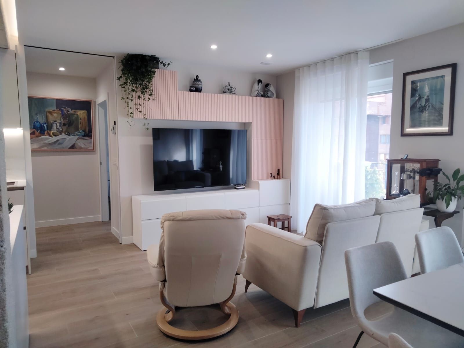 Una sala de estar con un sofá, un sillón y un televisor de pantalla plana.