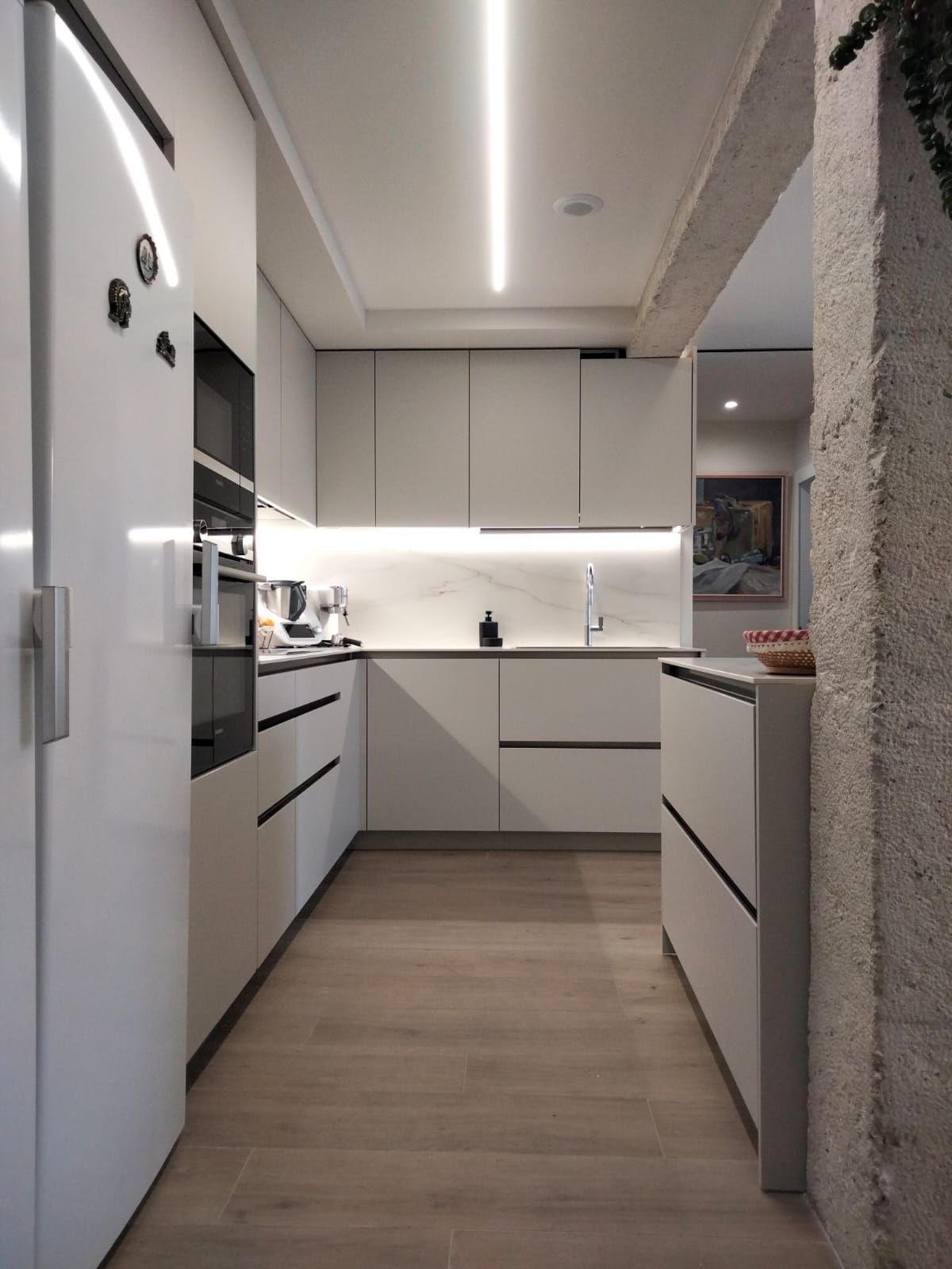 Una cocina con gabinetes blancos y pisos de madera.