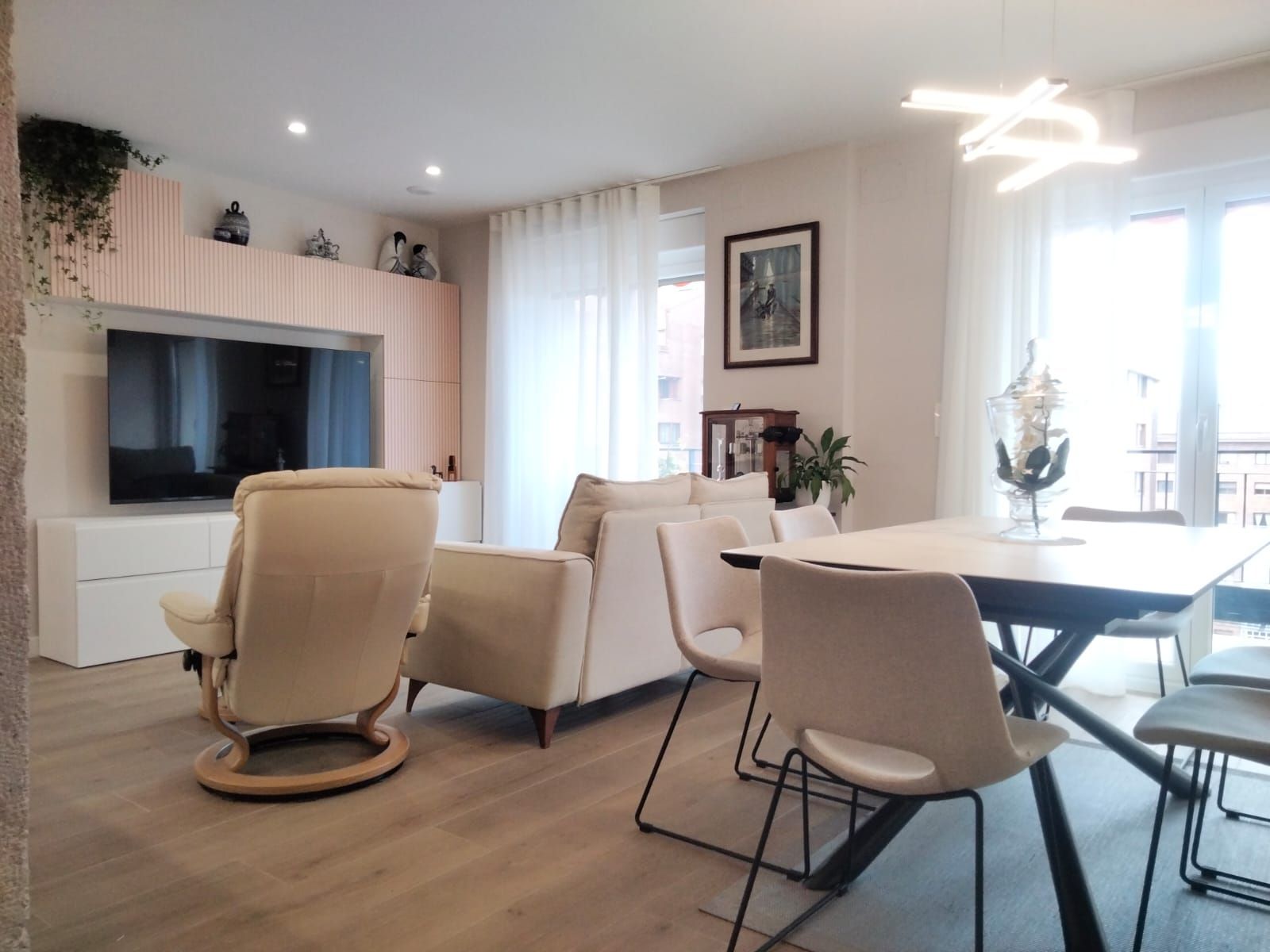 Una sala de estar con sofá, sillas, mesa y televisión.