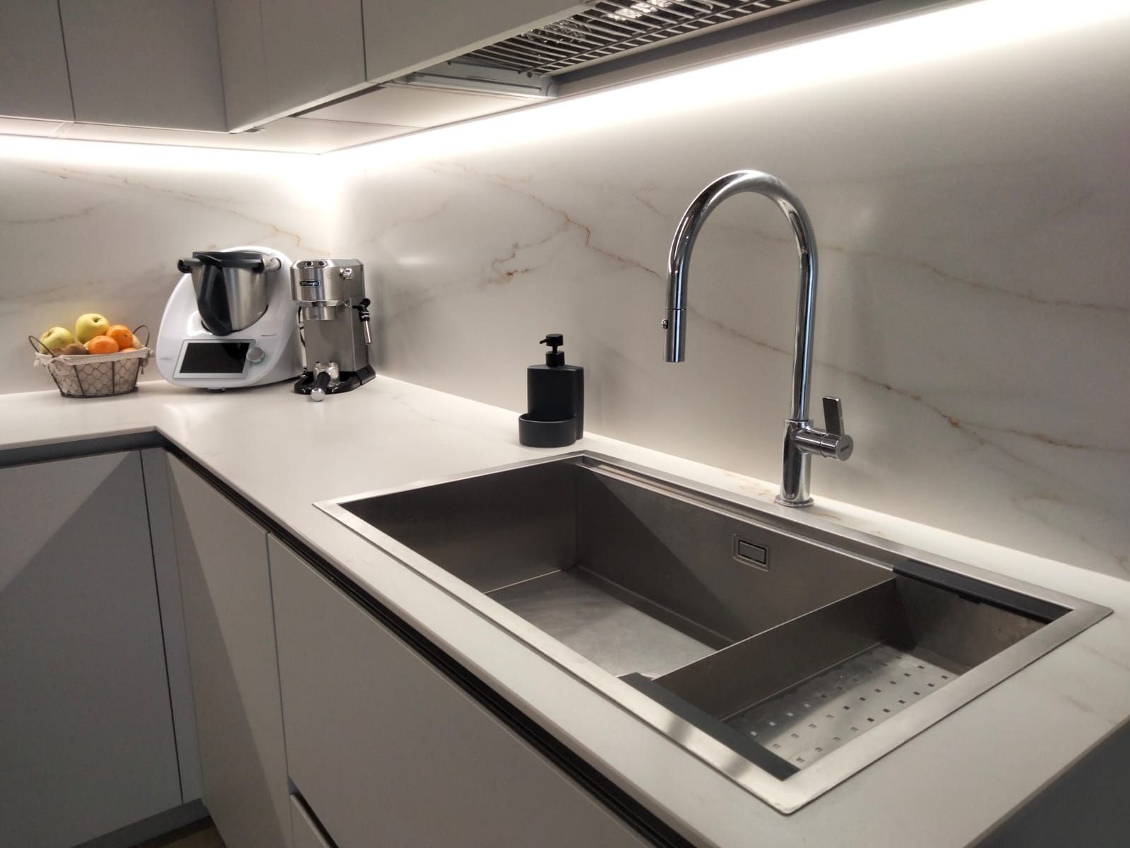 Una cocina con fregadero de acero inoxidable y mezclador